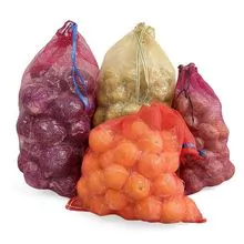 Patatas, cebollas, frutas y verduras leno bolsa de malla